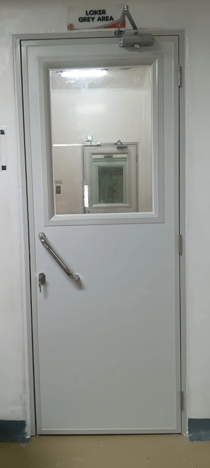 Pintu sandwich panel clean room dengan jendela intip besar dan door closer terpasang di area loker